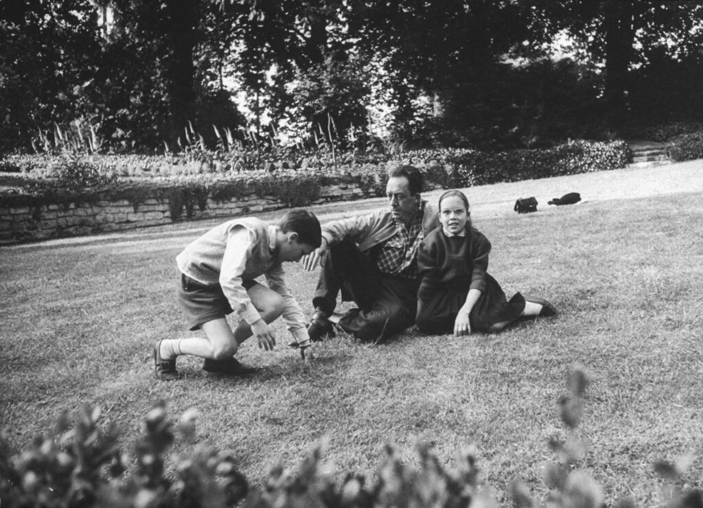 French author Albert Camus sitting in the garden of his Paris home with his 11-year-old twins Jean and Catherine, 1957.