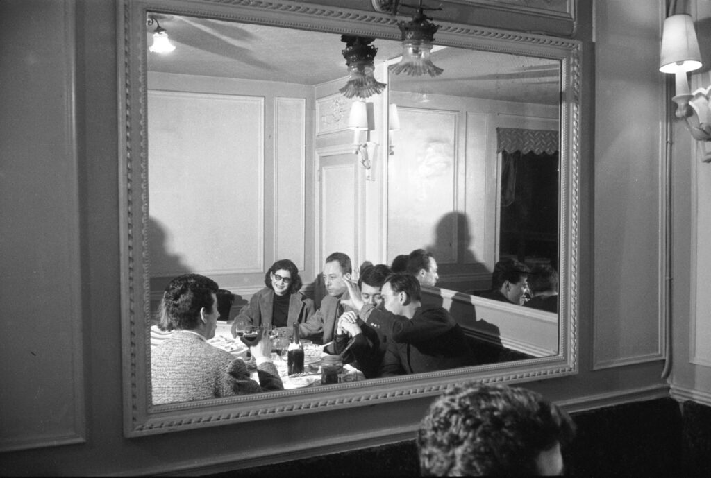 Albert Camus (center, next to woman in glasses) dined with a group at a Paris restaurant, 1957.