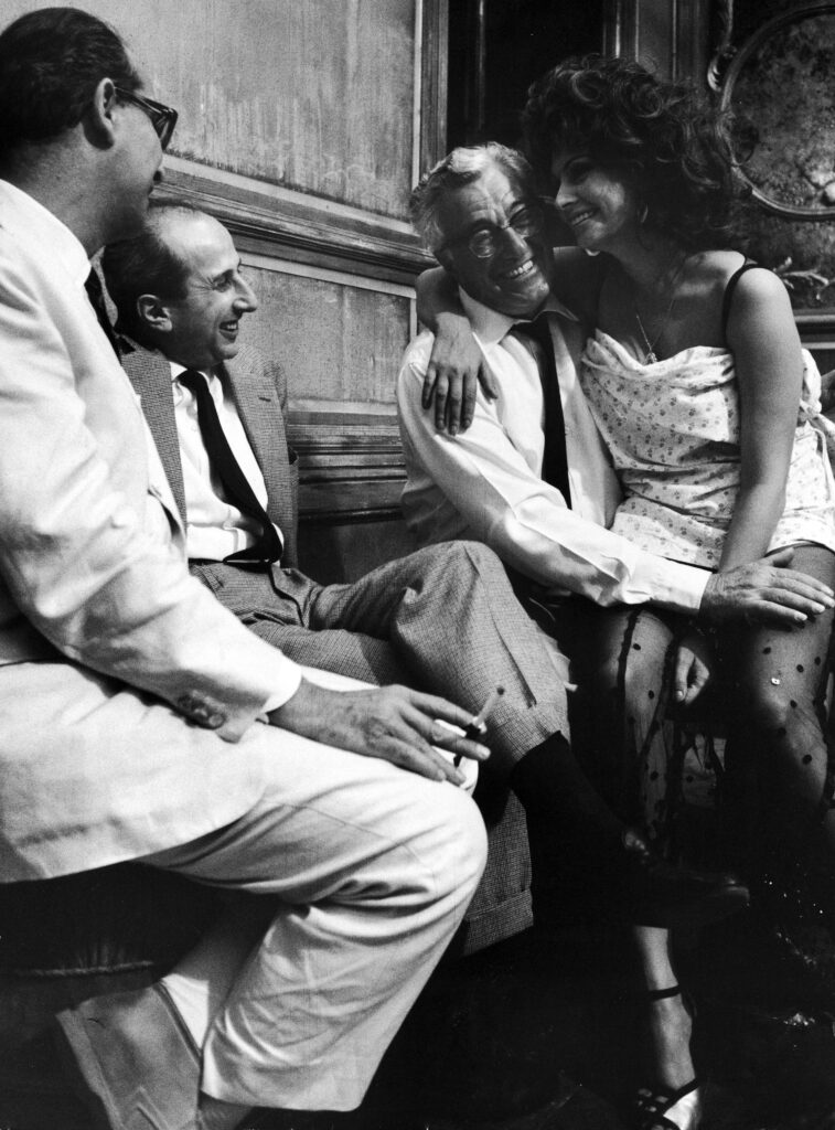 Sophia Loren sitting on director Vittorio de Sica's lap during the making of the 1964 film Marriage, Italian Style.